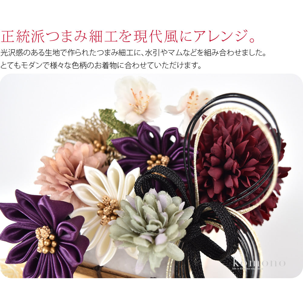 正統派つまみ細工を現代風にアレンジ。流行のくすみカラーで仕上げました。くすみカラーは原色よりも肌に馴染みやすく、顔まわりを華やかな雰囲気に演出してくれます。光沢感のある生地で作られたつまみ細工に、水引やマムなどを組み合わせました。